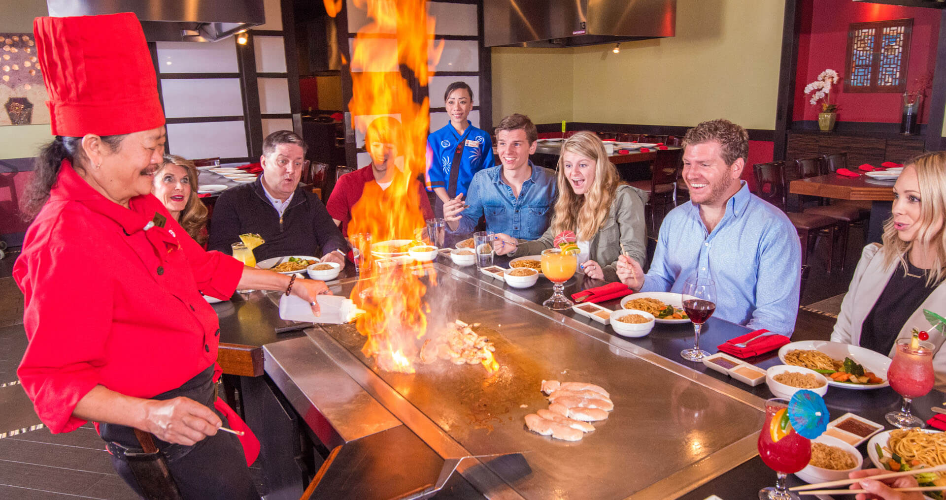 Kobe chef setting food on fire while people around the table watch in amazement