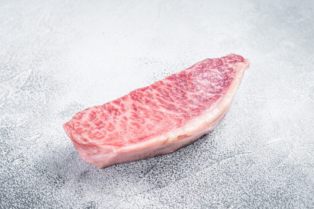 Raw wagyu rump sirloin steak, kobe beef meat. White background. Top view.