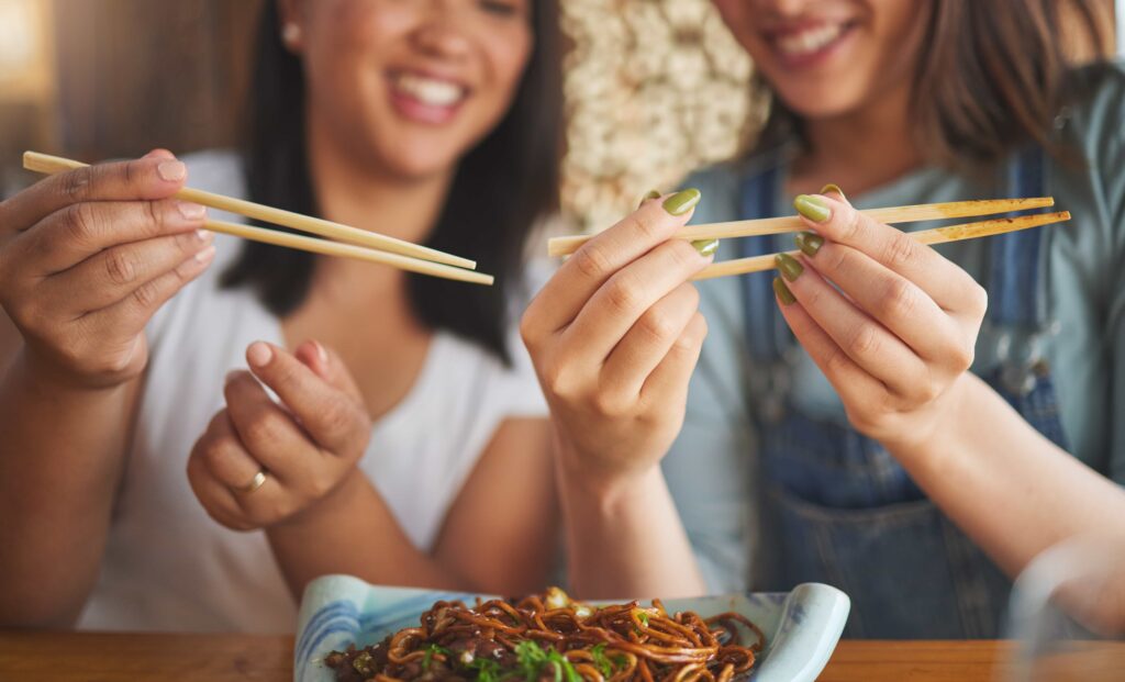 Friends learning how to use chopsticks